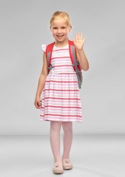 childhood, education and people concept - happy student girl with school bag waving hand over grey background. happy student girl with school bag waving hand
