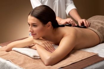 wellness, beauty and relaxation concept - beautiful young woman having hot stone massage at spa. beautiful woman having hot stone massage at spa