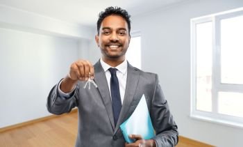 real estate business and people concept - indian man realtor with keys and folder over empty new apartment room background. indian man realtor with home keys and folder