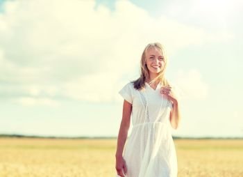 happiness, nature, summer, vacation and people concept - happy smiling young woman or teenage girl on cereal field. happy young woman or teenage girl on cereal field