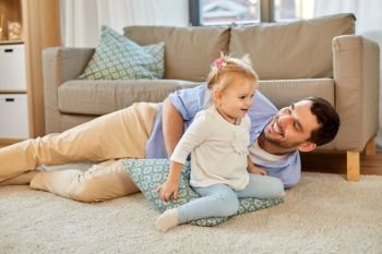 family, parenthood and fatherhood concept - happy father and little baby daughter playing with pillow at home. father with little baby daughter at home