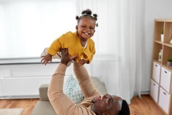 family, fatherhood and people concept - happy african american father playing with baby daughter at home. happy african american father with baby at home