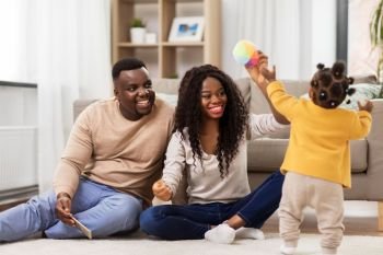 family, parenthood and people concept - happy african american mother and father playing with baby daughter at home. african family playing with baby daughter at home