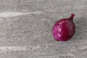 vegetable, food and culinary concept - red onion on wet slate stone background. red onion on wet slate stone background