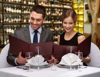 leisure and luxury concept - smiling couple with menus over restaurant or wine bar background. smiling couple with menus at restaurant
