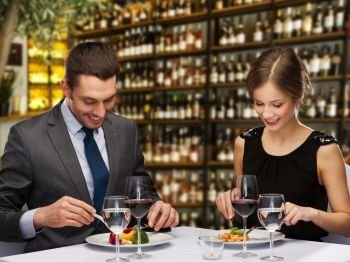 leisure and luxury concept - smiling couple eating main course over restaurant or wine bar background. smiling couple eating main course at restaurant