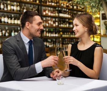 leisure and luxury concept - smiling couple clinking glasses of champagne over restaurant or wine bar background. couple with glasses of champagne at restaurant