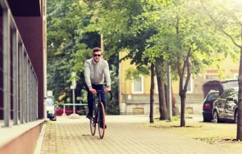 lifestyle, transport and people concept - young man in sunglasses riding bicycle on city street. young man riding bicycle on city street
