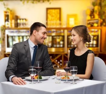 leisure and luxury concept - smiling couple with food and wine over restaurant or wine bar background. smiling couple with food and wine at restaurant