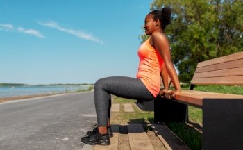 fitness, sport and healthy lifestyle concept - young african american woman exercising with bench at seaside. african american woman doing sports at seaside