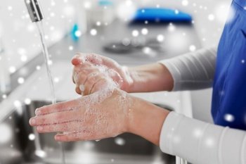 hygiene, health care and safety concept - close up of female doctor or nurse washing hands with soap and water at hospital in winter over snow. doctor or nurse washing hands with liquid soap