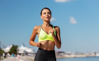 fitness, sport and healthy lifestyle concept - young woman running at seaside. young woman running at seaside