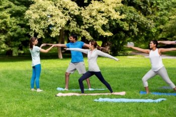 fitness, sport and healthy lifestyle concept - group of happy people doing yoga with coach at summer park. group of people doing yoga at summer park