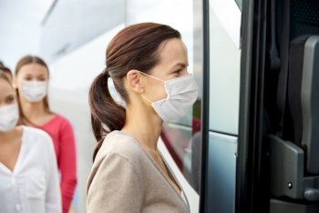 tourism and health concept concept - group of female passengers wearing face protective medical mask for protection from virus disease boarding travel bus. group of passengers in masks boarding travel bus