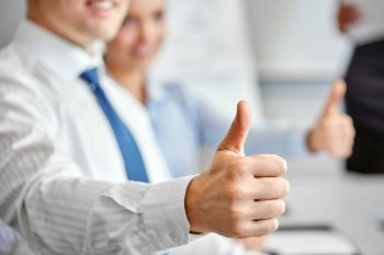 success, people and teamwork concept - close up of happy business team showing thumbs up at office. close up of businessman showing thumbs up