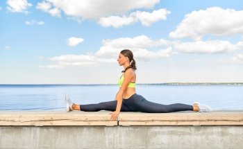 fitness, sport and healthy lifestyle concept - young woman doing full split at seaside. young woman doing full split at seaside