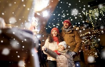 family, winter holidays and celebration concept - happy mother, father and little daughter at christmas market on town hall square in tallinn, estonia over snow. happy family at christmas market in city