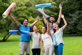 fitness, sport and healthy lifestyle concept - group of happy people with yoga mats waving hands at park. group of happy people with yoga mats at park