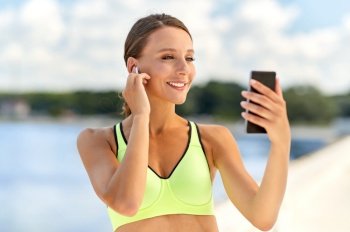fitness, sport and healthy lifestyle concept - happy smiling young woman with earphones and smartphone exercising outdoors. woman with earphones and smartphone doing sports