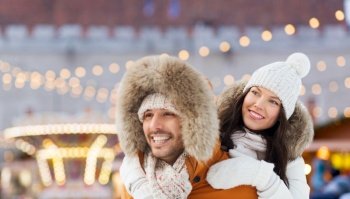 winter holidays, leisure and people concept - happy couple having fun over christmas market background. happy couple over christmas market background