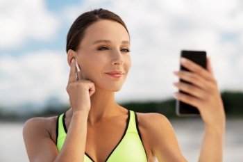 fitness, sport and healthy lifestyle concept - young woman with earphones and smartphone exercising outdoors. woman with earphones and smartphone doing sports