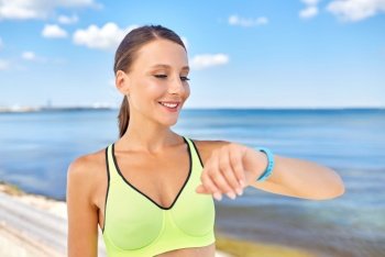 sport, technology and healthy lifestyle concept - happy smiling young woman with fitness tracker outdoors. smiling young woman with fitness tracker outdoors