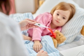 healthcare, medicine and people concept - close up of doctor with thermometer measuring temperature of little sick girl lying in bed at home. doctor measuring sick girl’s temperature