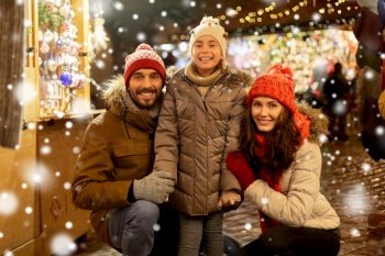 family, winter holidays and celebration concept - happy mother, father and little daughter at christmas market on town hall square in tallinn, estonia over snow. happy family at christmas market in city