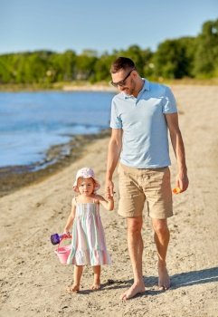 family, fatherhood and leisure concept - happy father walking with little daughter on beach. happy father walking with little daughter on beach