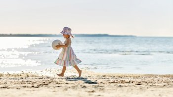 childhood, leisure and people concept - happy little baby girl with ball running along summer beach. happy baby girl with ball running on summer beach
