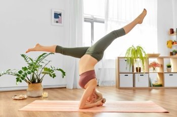 pregnancy, sport and people concept - happy pregnant woman doing yoga headstand split at home. pregnant woman doing yoga headstand split at home