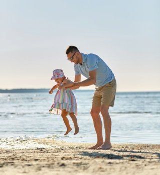 family, fatherhood and leisure concept - happy father playing with little daughter on beach. happy father playing with little daughter on beach