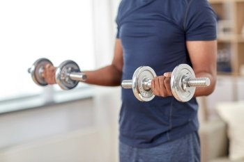 fitness, sport, weightlifting and bodybuilding concept - man exercising with dumbbells at home. man exercising with dumbbells at home