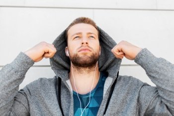 fitness, sport and lifestyle concept - young man in earphones listening to music outdoors. man in earphones listening to music outdoors