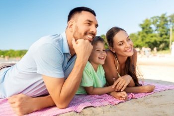family, leisure and people concept - happy mother, father and son lying on summer beach. family lying on summer beach
