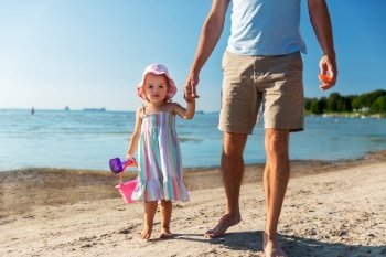 family, fatherhood and leisure concept - father walking with little daughter on beach. father walking with little daughter on beach