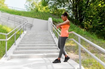 technology, sport and people concept - happy smiling young african american woman with fitness tracker outdoors. happy african woman with fitness tracker outdoors