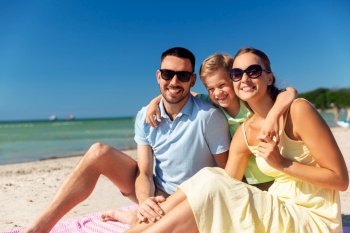 family, leisure and people concept - happy mother, father and little son hugging on summer beach. family hugging on summer beach