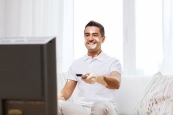skin health, technology and entertainment concept - smiling middle aged man with vitiligo watching tv at home. smiling middle aged man with vitiligo watching tv