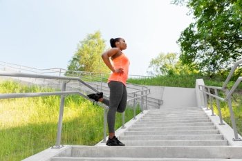 fitness, sport and healthy lifestyle concept - young african american woman stretching outdoors. young african american woman stretching outdoors