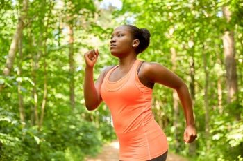 fitness, sport and healthy lifestyle concept - young african american woman running in forest. young african american woman running in forest