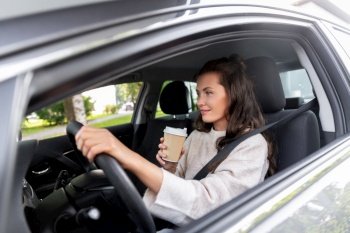 lifestyle and people concept - happy smiling young woman or female driver driving car and drinking takeaway coffee. woman or female driver with coffee driving car