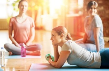 fitness, people and healthy lifestyle concept - group of women in yoga class resting on mats at studio. group of women resting on yoga mats at studio