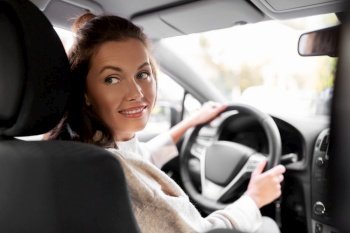 safety and people concept - happy smiling young woman or female driver driving car in city. smiling woman or female driver driving car in city