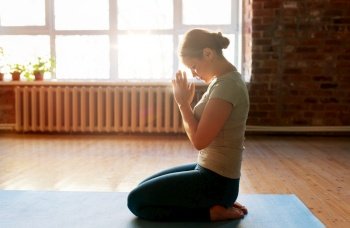 religion, meditation and people concept - close up of woman meditating at yoga studio or praying. close up of woman meditating at yoga studio