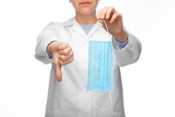 medicine, health protection and healthcare concept - close up of female doctor with medical mask showing thumbs down over white background. female doctor with mask showing thumbs down