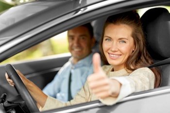 driver courses and people concept - car driving school instructor and young woman showing thumbs up to drive. car driving instructor and woman showing thumbs up