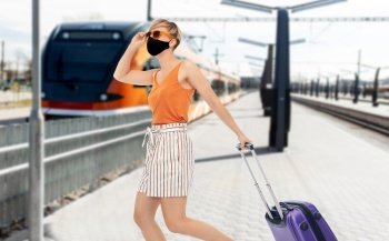 tourism, vacation and people concept - smiling young woman or teenage girl with travel bag over train on railway station on background. woman in mask with travel bag over train