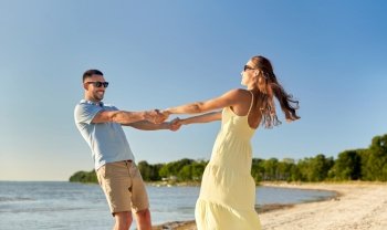 leisure, relationships and people concept - happy couple in sunglasses holding hands on summer beach. happy couple holding hands on summer beach