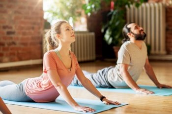 fitness, people and healthy lifestyle concept - man and woman doing cobra pose on mats at yoga studio. man and woman doing yoga cobra pose at studio